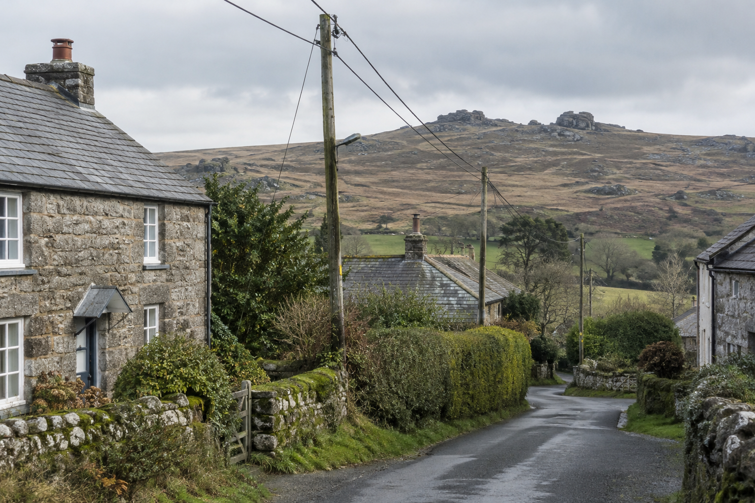 Overhead electricity lines beside granite cottages and a rural lane on the edge of Dartmoor in Devon
